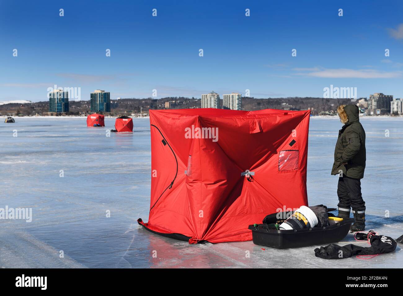 Barrie, Ontario, Kanada - 7. März 2021: Fischer errichten im Winter ein rotes Eisangelzelt auf der gefrorenen Kempenfelt Bay des Lake Simcoe Stockfoto