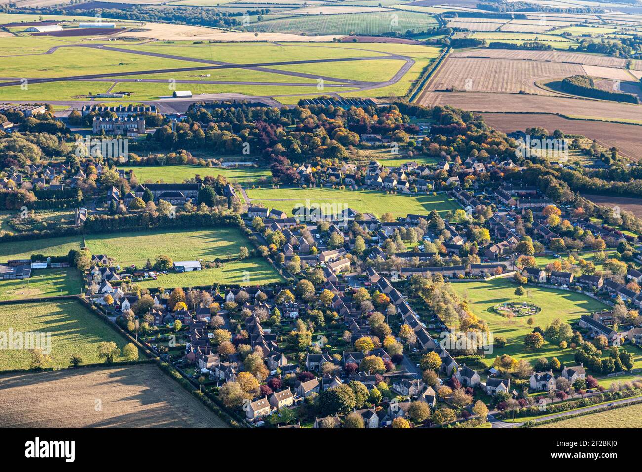 Eine Luftaufnahme des Cotswold-Dorfes Upper Rissington, Gloucestershire, UK - Little Rissington Airfield ist im Hintergrund zu sehen. Stockfoto