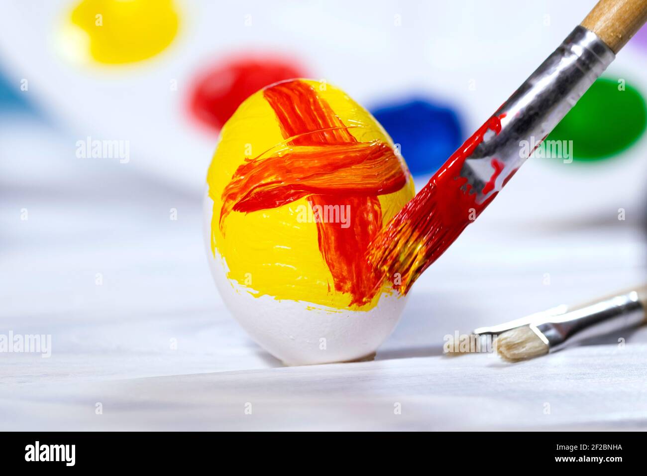 Ostereier malen, Vorbereitung für den Frühlingsurlaub, Gelbes und Rotes Ei mit Farbpalette auf blauem Hintergrund, Pinsel malen, Copyspace Stockfoto