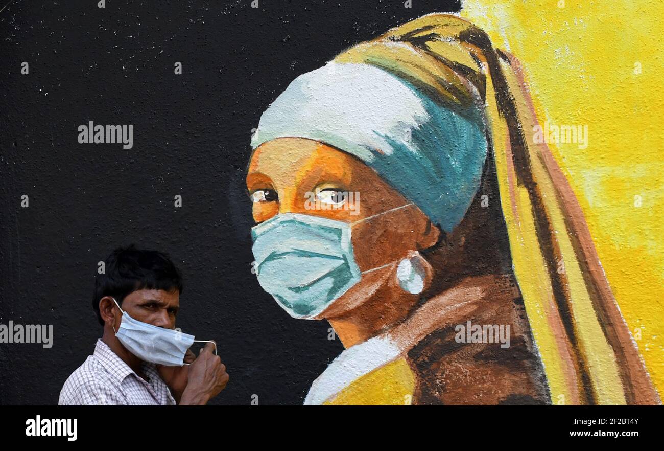 Ein Mann mit Gesichtsmaske geht an einem Graffiti von Girl with a Pear Earring des niederländischen Malers Johannes Vermeer in Mumbai vorbei.Trotz der Spitze bei Coronavirus-Fällen im Bundesstaat Maharashtra halten sich die Menschen nicht an die Richtlinien der Regierung, soziale Distanz zu verfolgen, Maske tragen und Desinfektionsmittel verwenden. Stockfoto