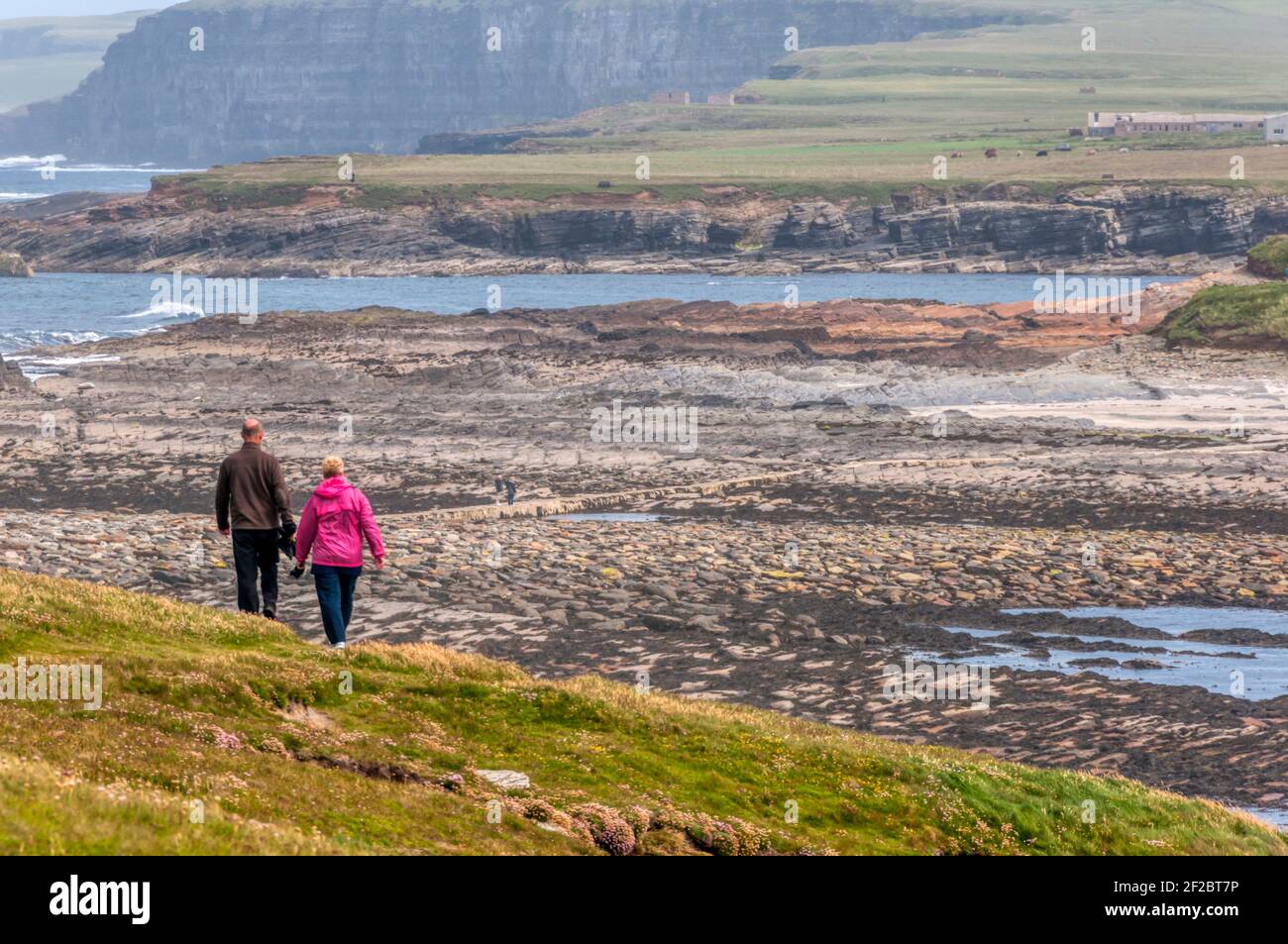 Blick von Brough of Birsay zurück zum Orkney Mainland mit Touristen, die über den Damm zurückkehren. Stockfoto