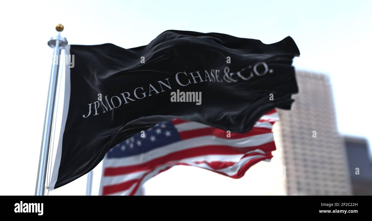 New York, USA, 28. Januar 2021: Flagge mit dem JPMorgan Chase & Co-Logo, die im Wind winkt, mit der amerikanischen Flagge im Hintergrund. JPMorgan Chase & Stockfoto