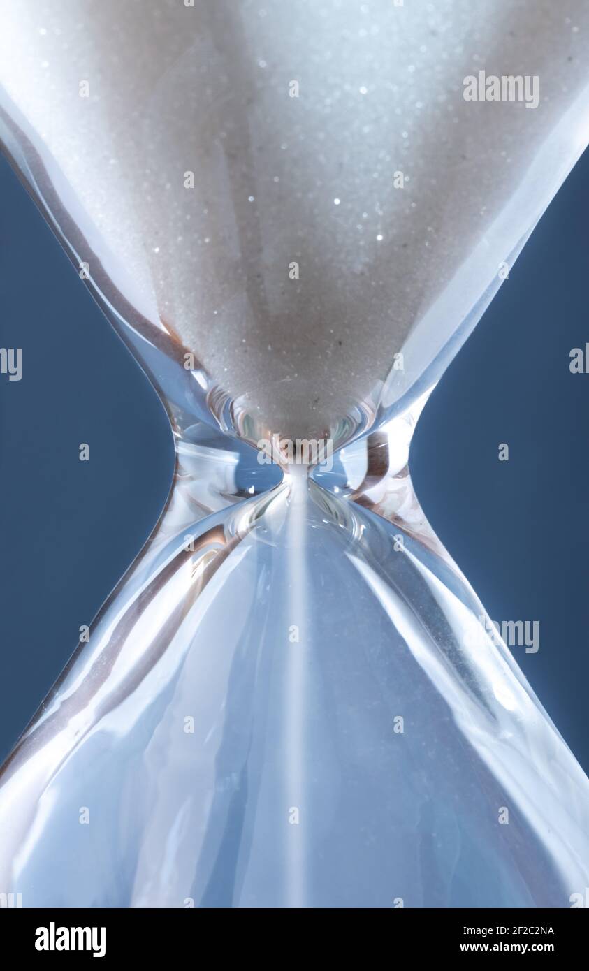 Sanduhr mit weißem Sand vor blauem Hintergrund Stockfoto