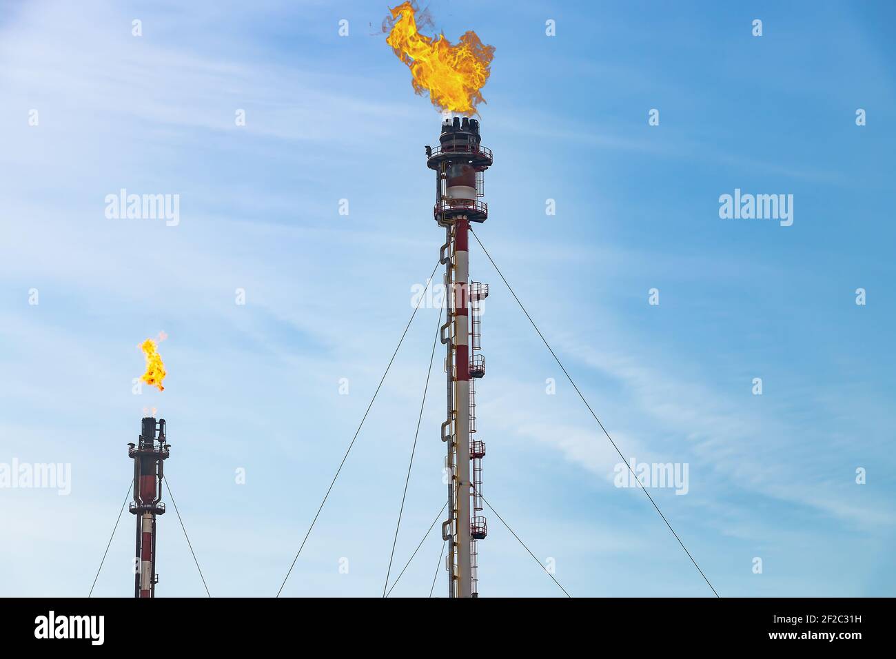 Abgaskamine der petrochemischen Industrie mit brennender Flamme von Palos de la Frontera in Huelva, Andalusien, Spanien. Stockfoto