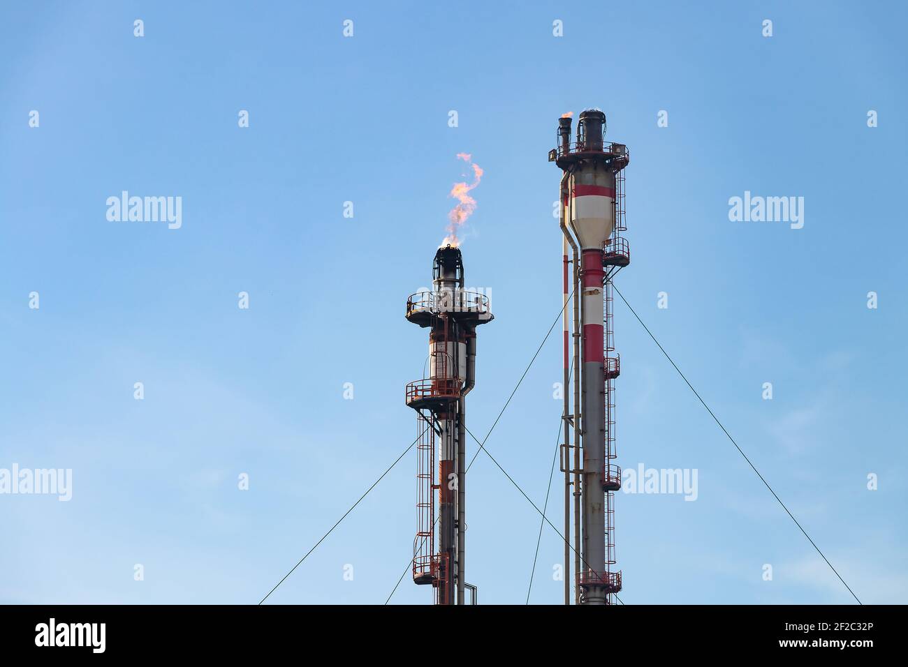 Abgaskamine der petrochemischen Industrie mit brennender Flamme von Palos de la Frontera in Huelva, Andalusien, Spanien. Stockfoto