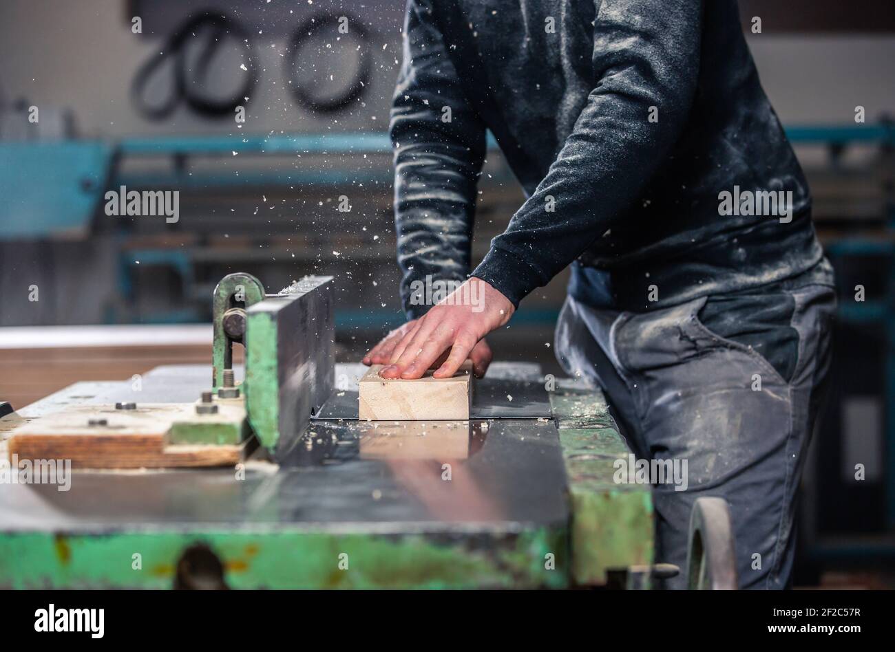 Professioneller Zimmermann fräst das Holz auf der riesigen Säge für ein modernes Möbel-, Schreinerei- und Holzwerkkonzept Stockfoto