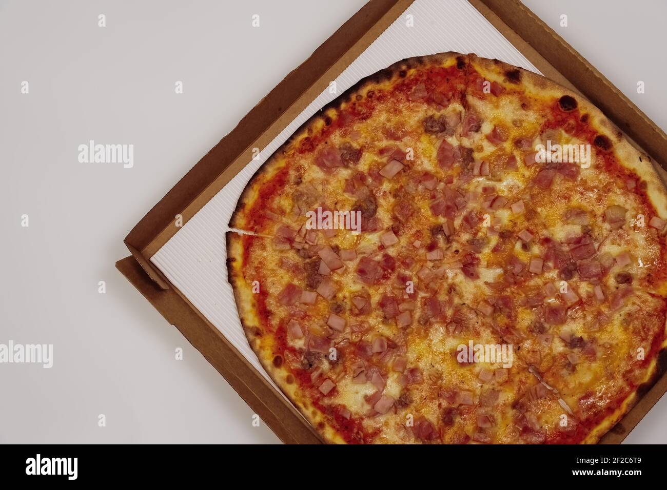 Pizza auf einem Karton Draufsicht, vor weißem Hintergrund. Nahaufnahme von tiefem Gericht traditionelle italienische Stil Lebensmittel Lieferung. Stockfoto