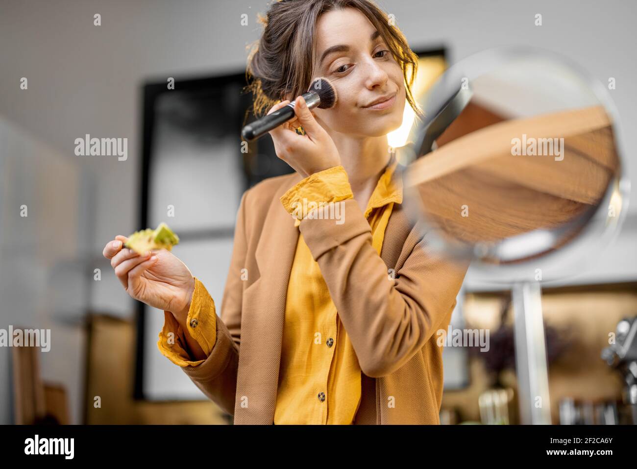 Pingelige junge Geschäftsfrau in Eile, um am Morgen zu arbeiten, Frühstück zu essen und sich unterwegs schminken Stockfoto