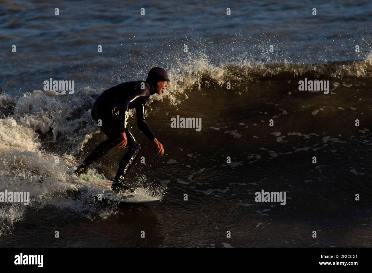 Ein Surfer am Coney Beach, Porthcawl bei Flut und starken Winden von 67mph trifft die South Wales Coast am 11th. März 2021. Kredit: Lewis Mitc Stockfoto