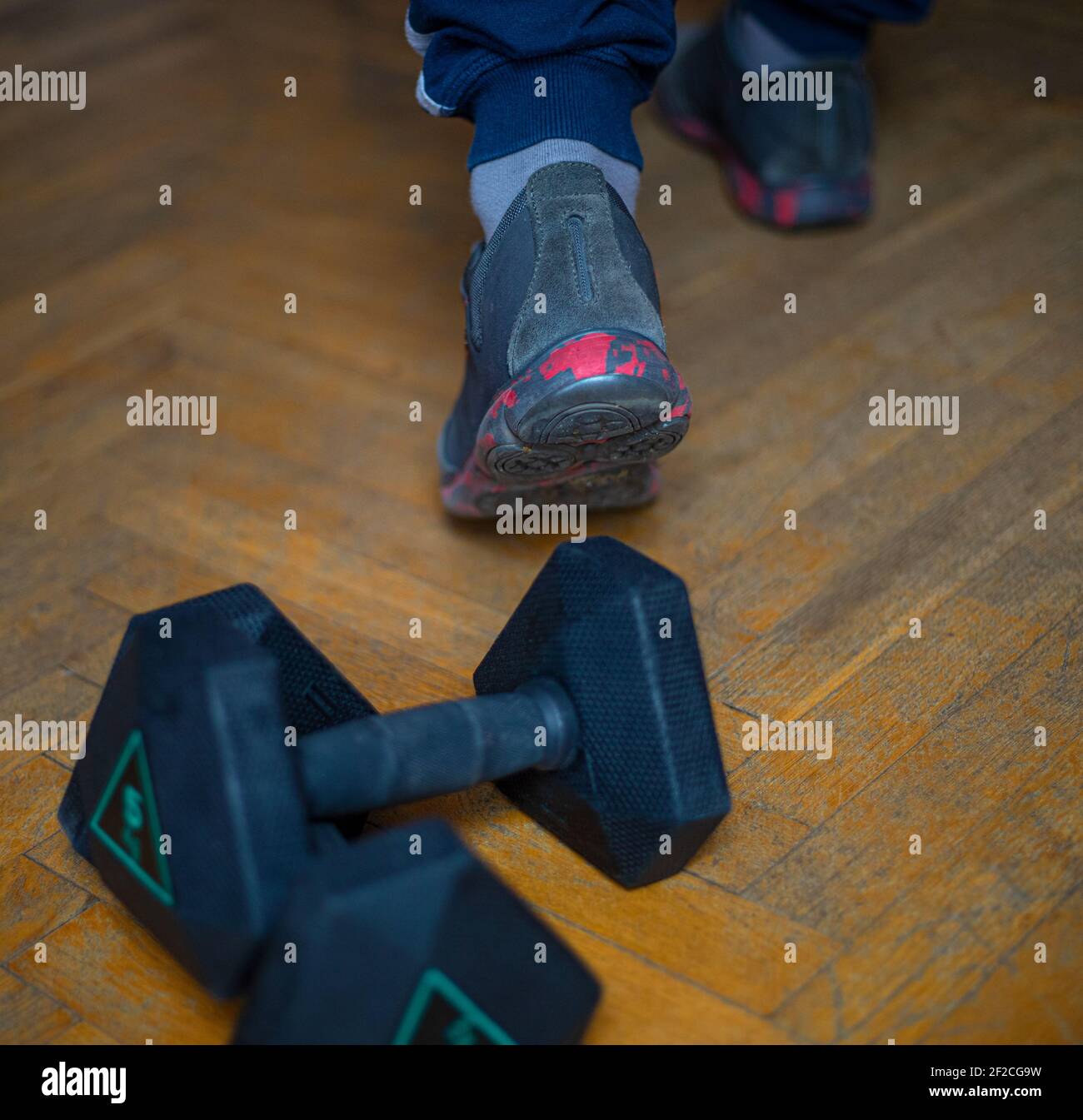 Training mit Gewichten beendet. Herren Sportschuhe für Bewegung, Laufen oder Laufen und 5 kg Hanteln auf einem Holzboden Stockfoto