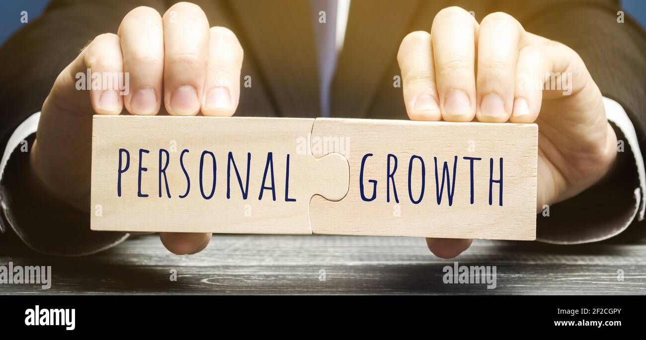 Holzpuzzles mit dem Wort Persönliches Wachstum in den Händen eines Geschäftsmannes. Selbstverbesserung von Fähigkeiten, Wissen, persönlichen Qualitäten und Lebenszielen. Stockfoto