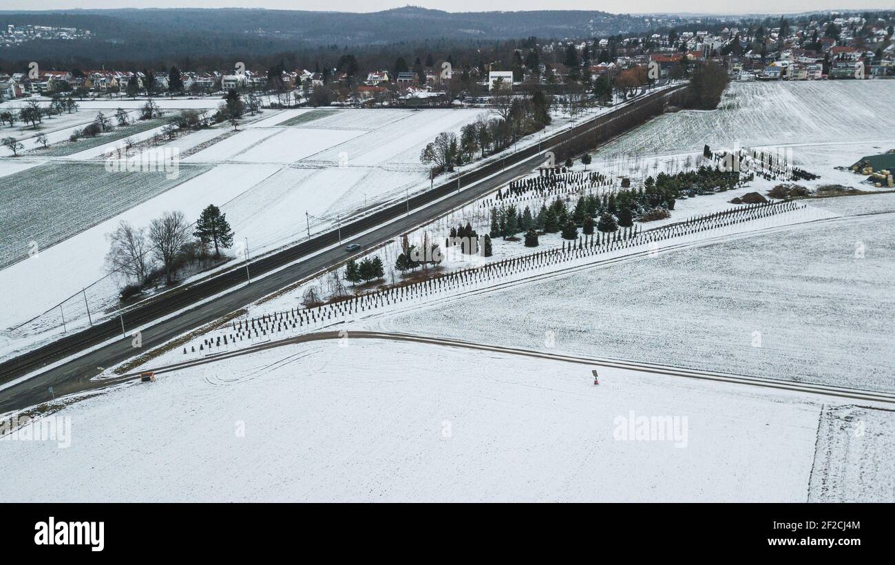 Landwirtschaftliche Landschaft in Deutschland im Winter. Bahngleise und eine Straße. Stockfoto