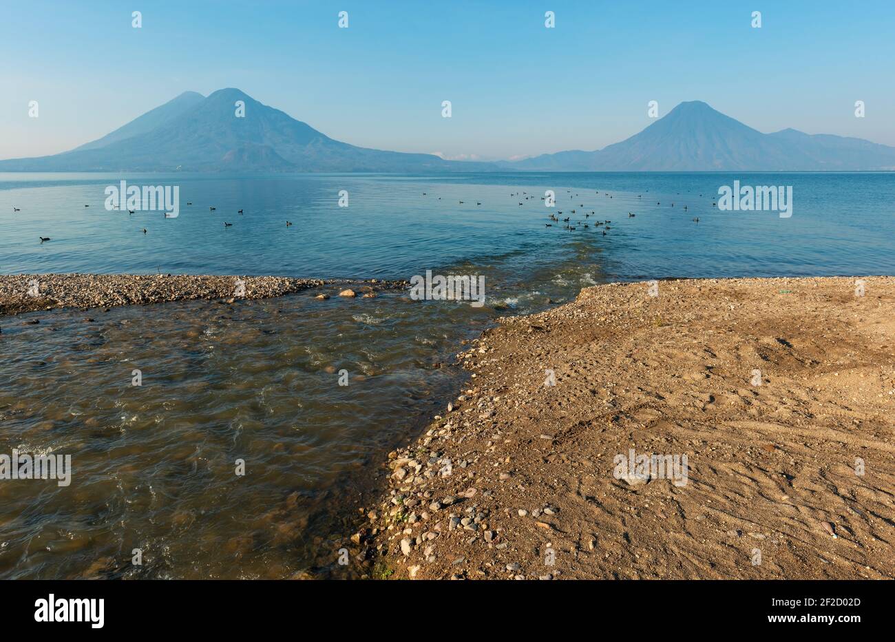 Ein Nebenfluss des Atitlan Sees in Panajachel mit Toliman, San Pedro und Atitlan Vulkan, Guatemala. Stockfoto Ein Nebenfluss des Atitlan Sees in Panajachel mit Toliman, San Pedro und Atitlan Vulkan, Guatemala. Stockfoto