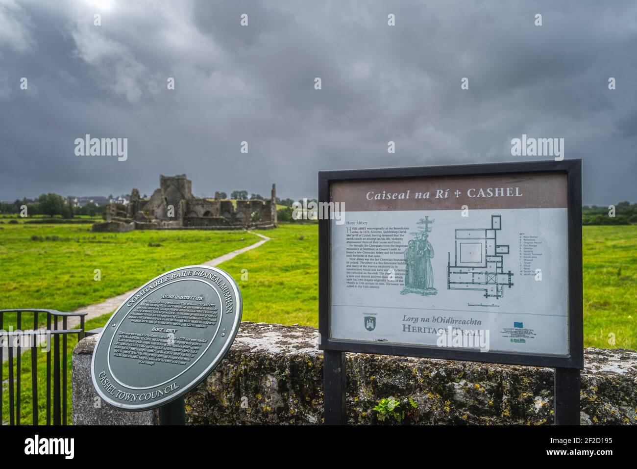 Cashel, Irland, August 2019 Informationstafel mit historischen Informationen über alte Ruinen der Hore Abbey mit dunklem dramatischen Sturmhimmel im Hintergrund Stockfoto