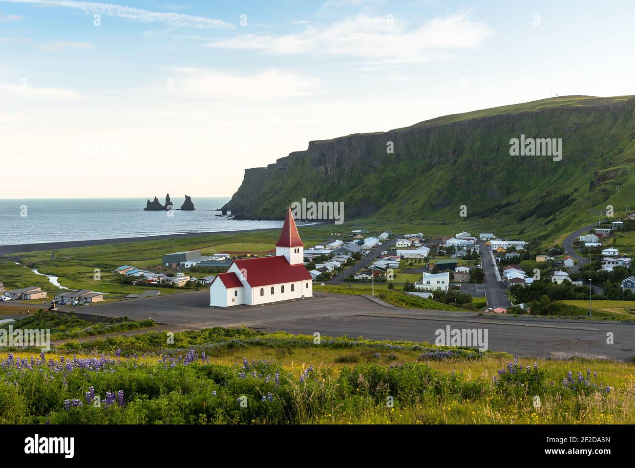 Schöne Aussicht auf die Küstenstadt Vik Island im Sommer. Im Vordergrund ist eine kleine Kirche zu sehen. Stockfoto