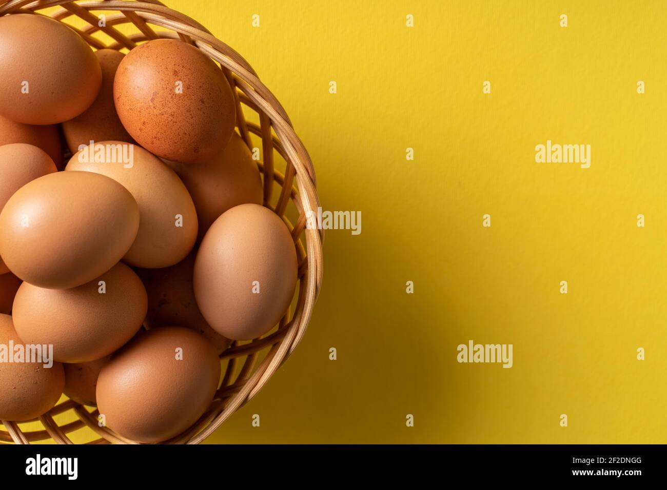 Draufsicht auf frische Bio-Eier im Korb auf der Gelber Hintergrund Stockfoto