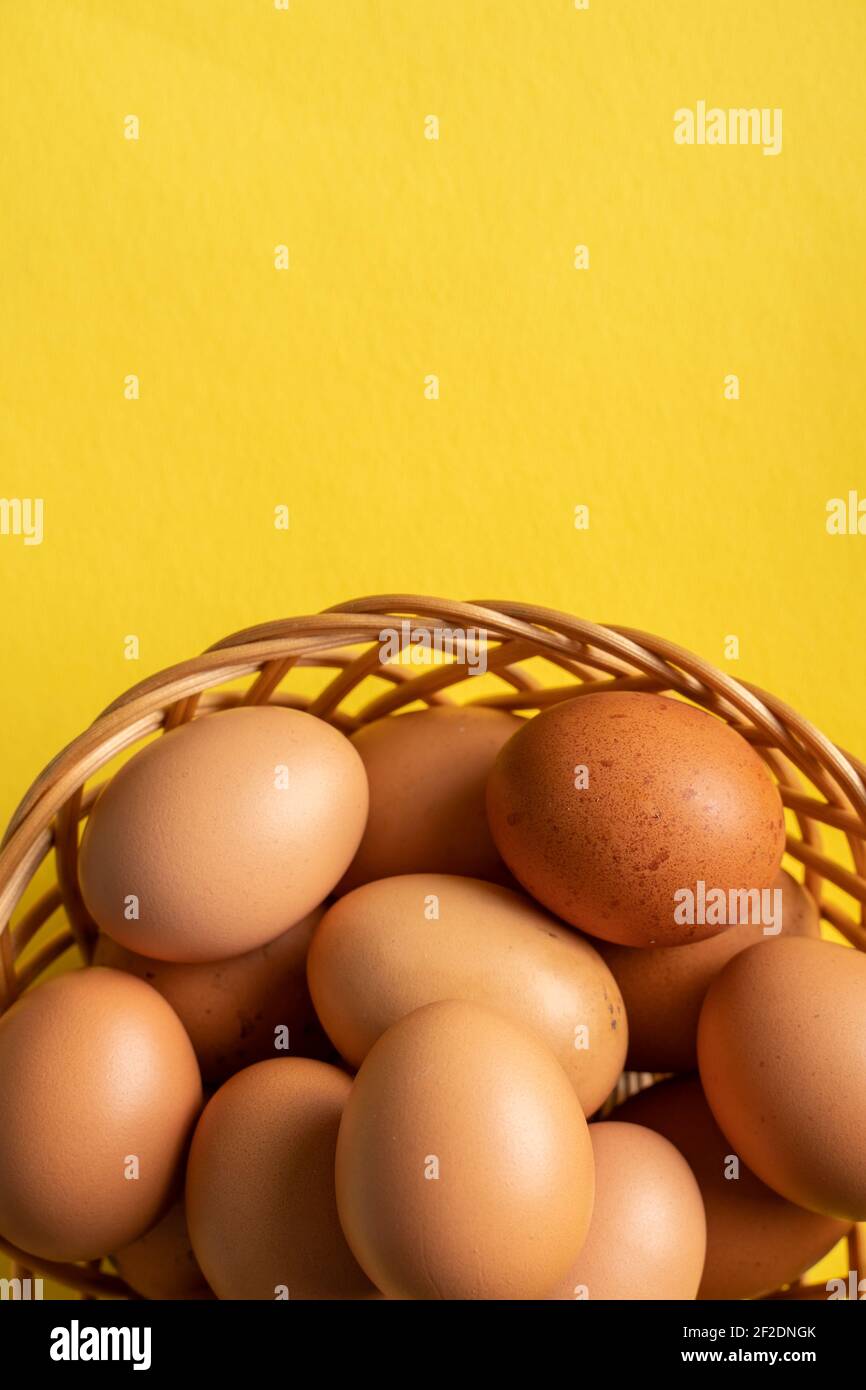 Draufsicht auf frische Bio-Eier im Korb auf der Gelber Hintergrund Stockfoto
