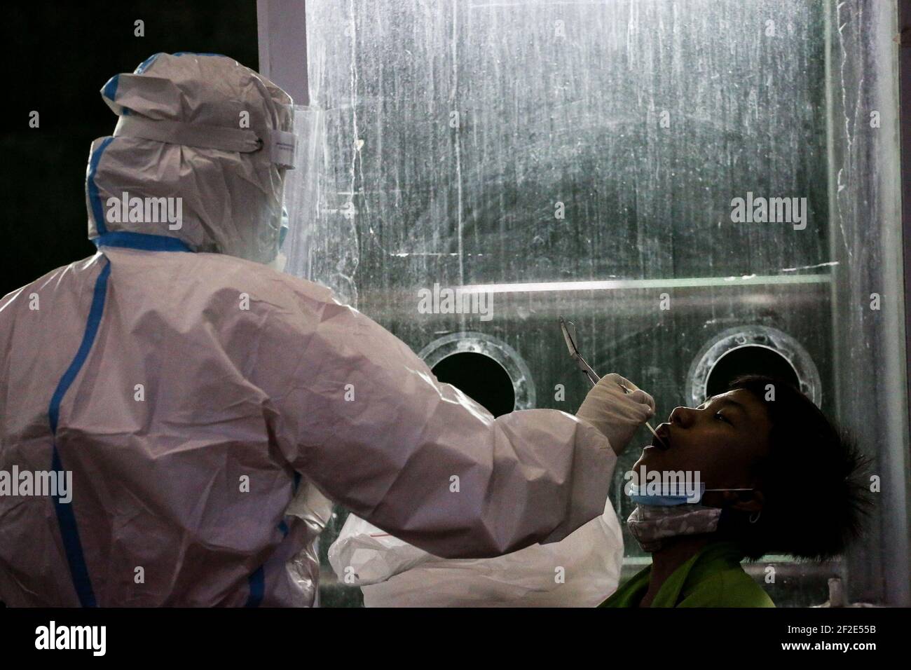 Ein Gesundheitarbeiter führt einen COVID-19 Abstrichtest an einem Kind in einer Turnhalle in Navotas Stadt, Manila, Philippinen durch. Stockfoto