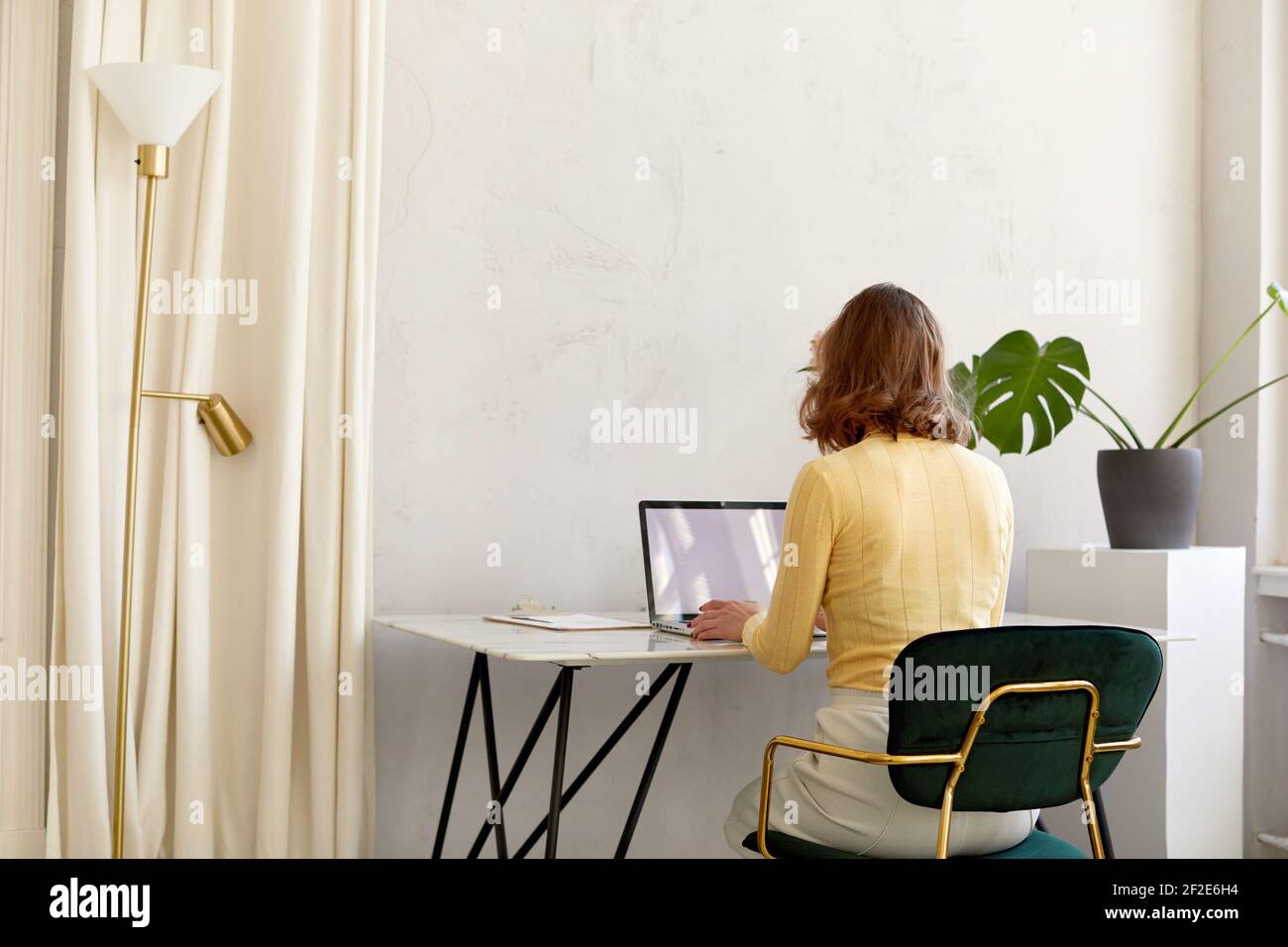 Rückansicht von unkenntlich weiblich in smart casual Kleidung sitzen Am Schreibtisch und beim Surfen auf Netbook mit leerem Bildschirm Während der Arbeit in stilvoller Wor Stockfoto
