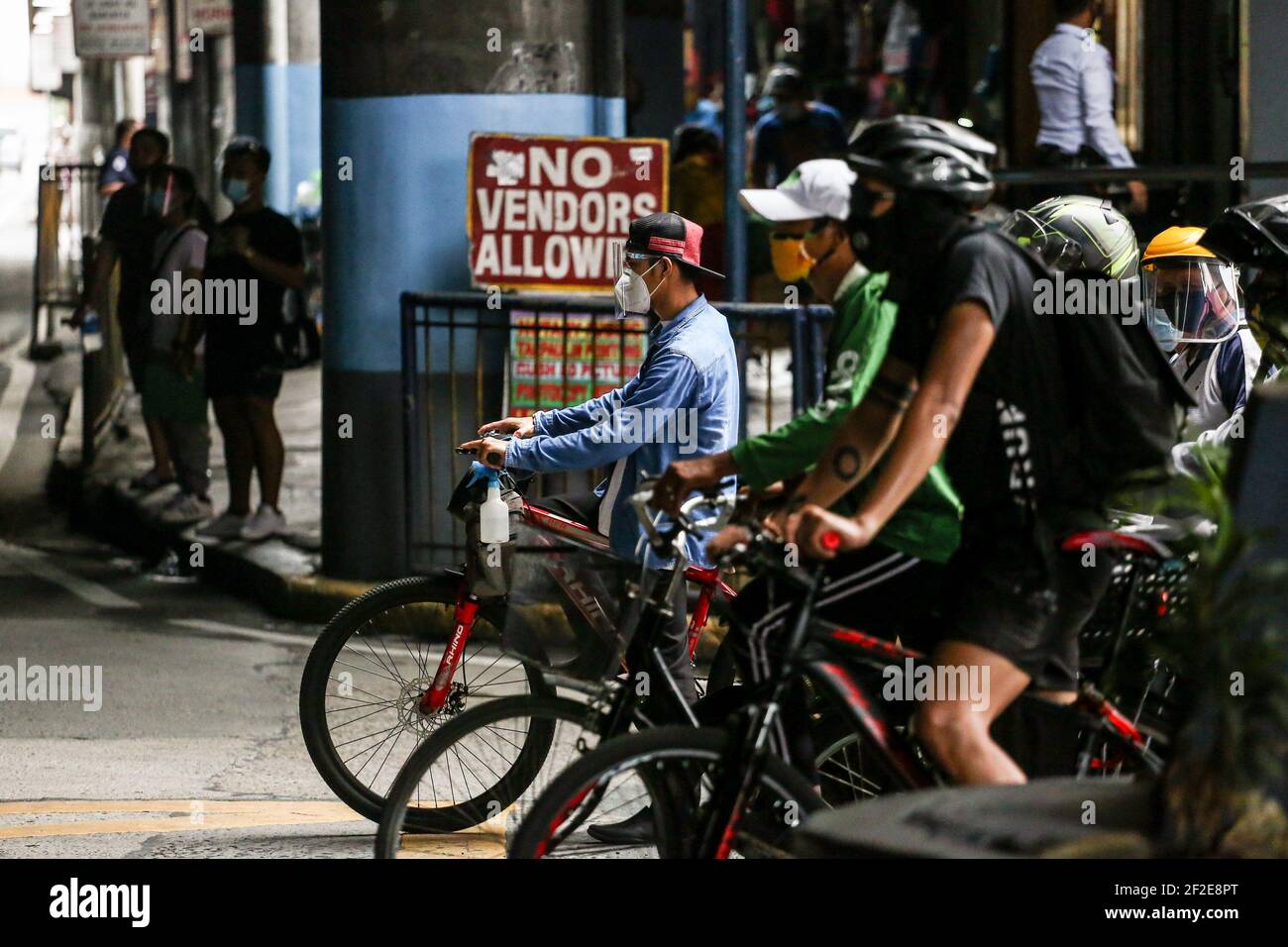 Ein Mann trägt eine Schutzmaske, während er mit dem Fahrrad eine Straße entlang fährt, da die COVID-19-Sperrbeschränkungen in Mandaluyong City, Metro Manila, Philippinen, lockern. Stockfoto