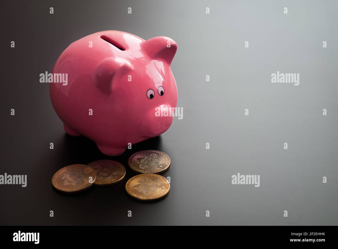 Haufen von wertvollen Bitcoins in der Nähe von Keramik rosa Sparschwein auf grauen Tisch platziert. Stockfoto
