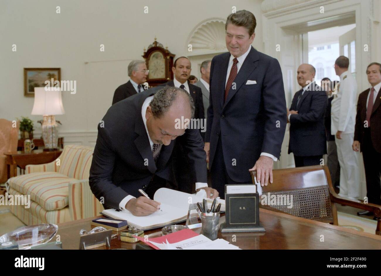 Präsident Sadat von der Arabischen Republik Ägypten unterschreibt das Gästebuch, während Präsident Ronald Reagan im Oval Office nachschaut. Stockfoto