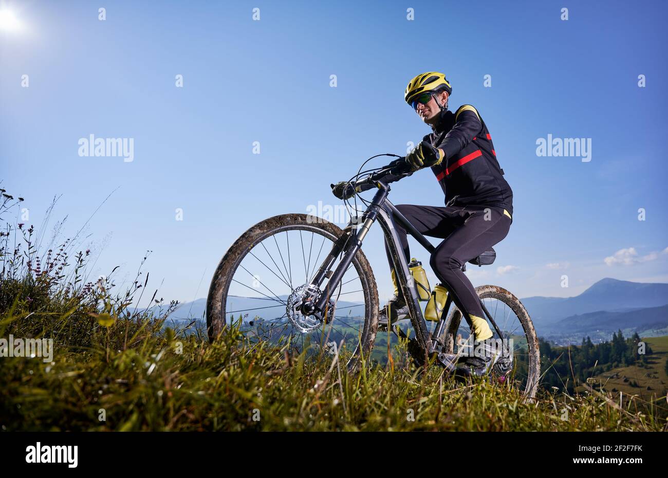 Fröhlicher Radler, der unter blauem Himmel Fahrrad bergauf fährt  Stockfotografie - Alamy