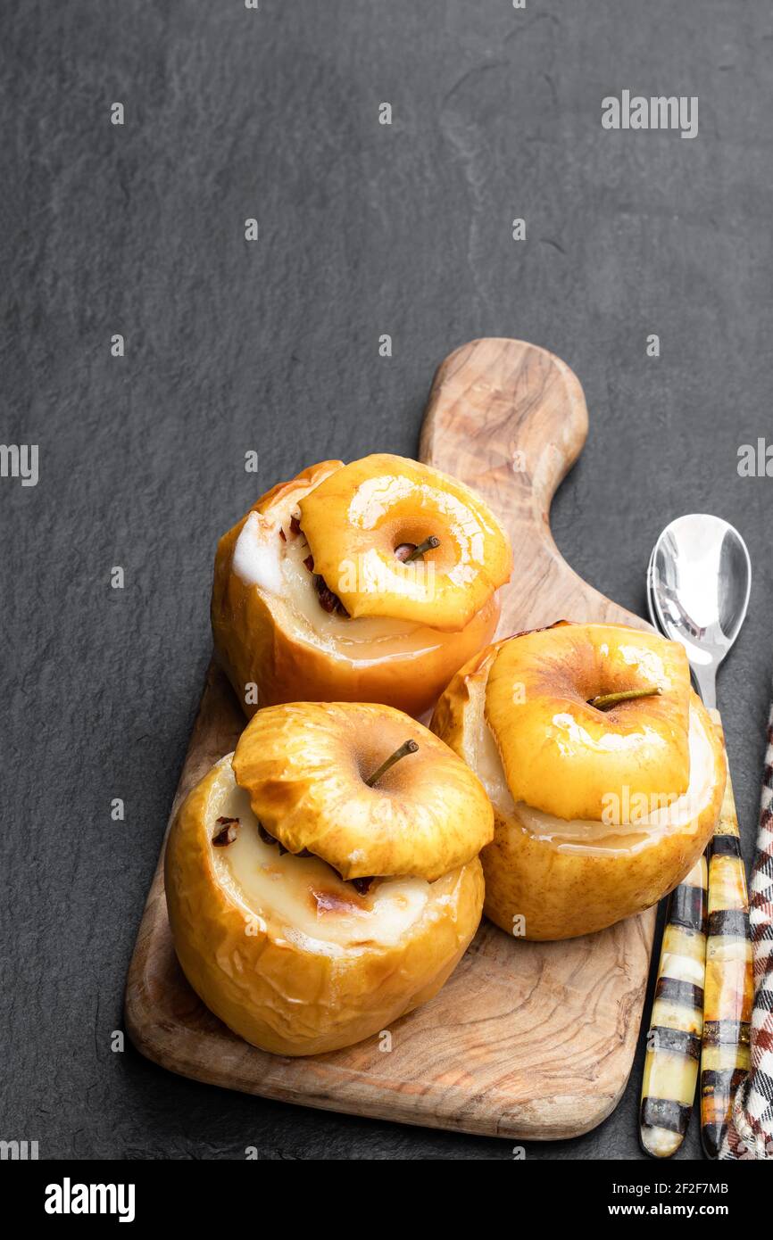 Gebackene Äpfel gefüllt mit Weichkäse und Nüssen auf schwarz Steinhintergrund Stockfoto