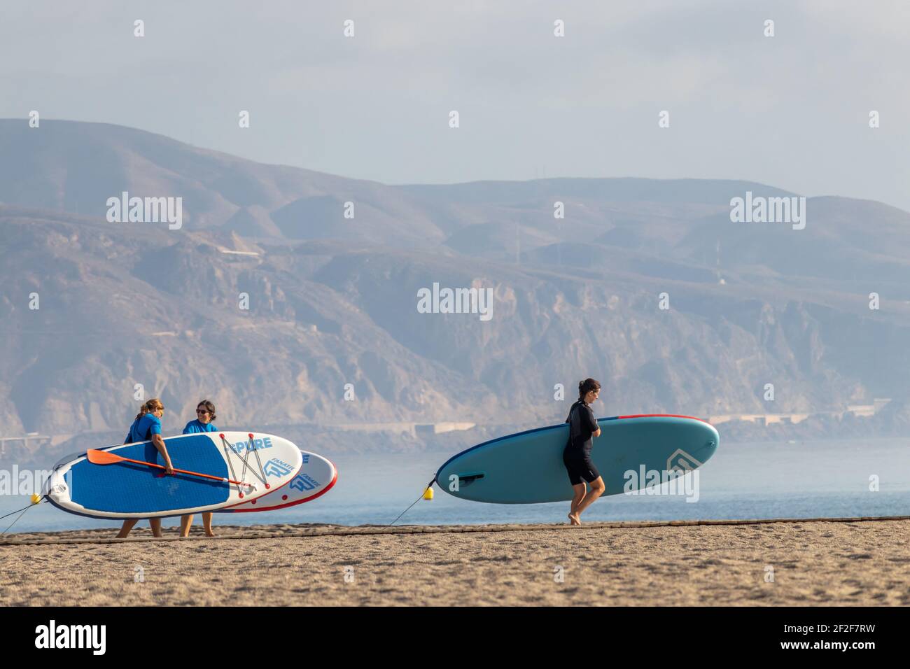 Almeria, Spanien. Oktober 10 202. Menschen, die mit ihren Paddelsurfen am Strand von Roquetas de Mar in Andalusien wandern Stockfoto