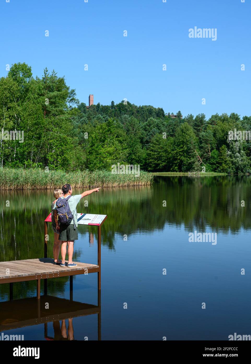Zwei Reisende genießen Sommertag in der Natur. Am hölzernen Pier stehend und auf die Wasseroberfläche blickend. Stockfoto