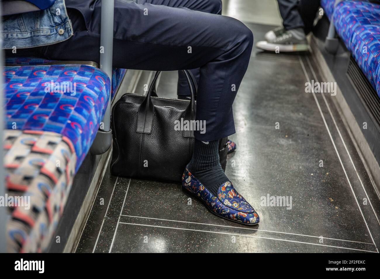 Mann mit bunten Slipper-Schuhen auf der Fahrt mit der Londoner U-Bahn, England, Großbritannien Stockfoto