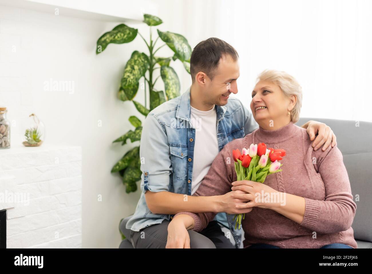 Schöner Sohn kommt nach Hause und trägt Blumenstrauß zu Seine Mutter  Stockfotografie - Alamy