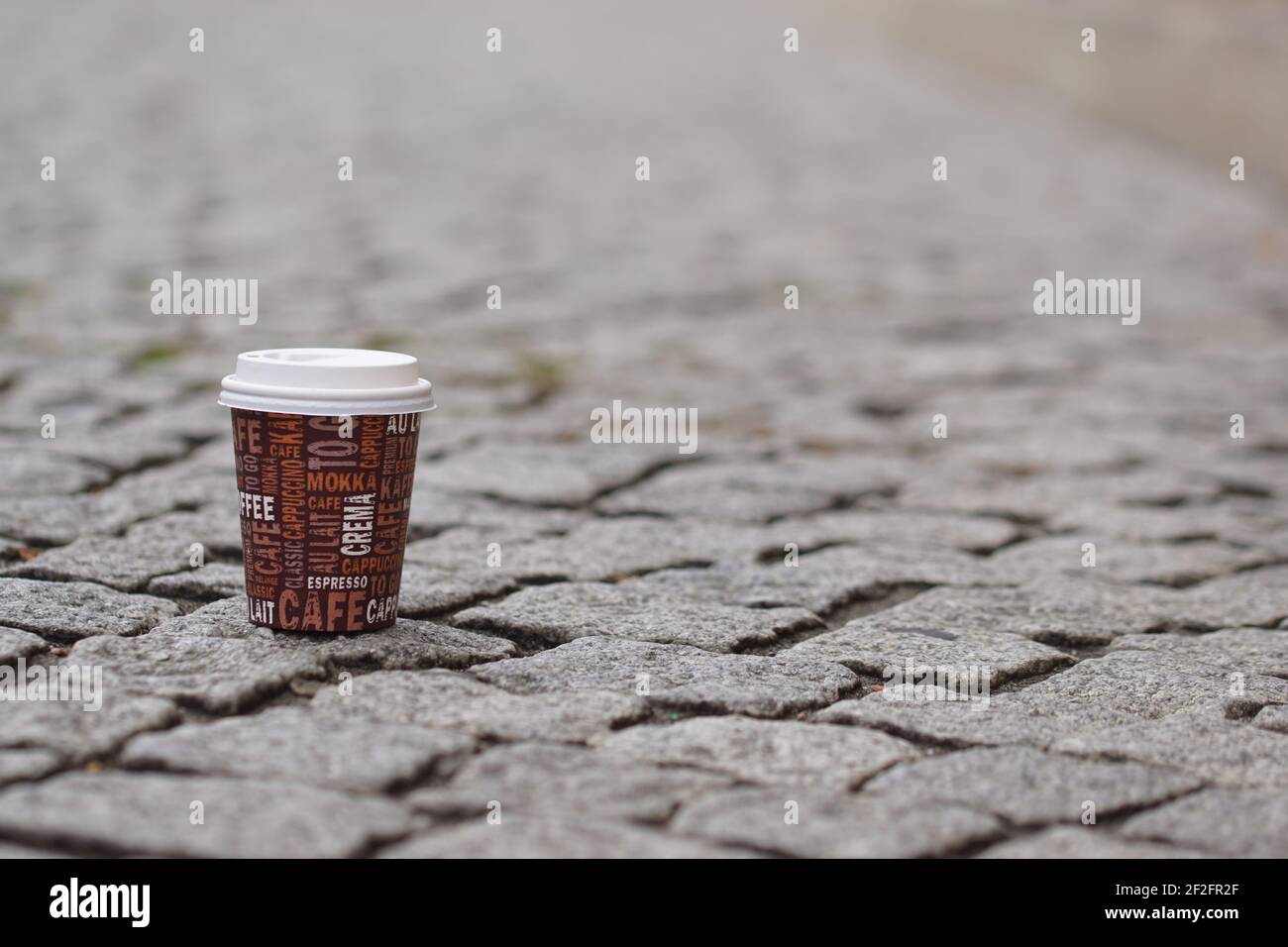 Einweg-Kaffee zu gehen Tasse stehen auf Kopfsteinpflaster Boden in Stadt Stockfoto