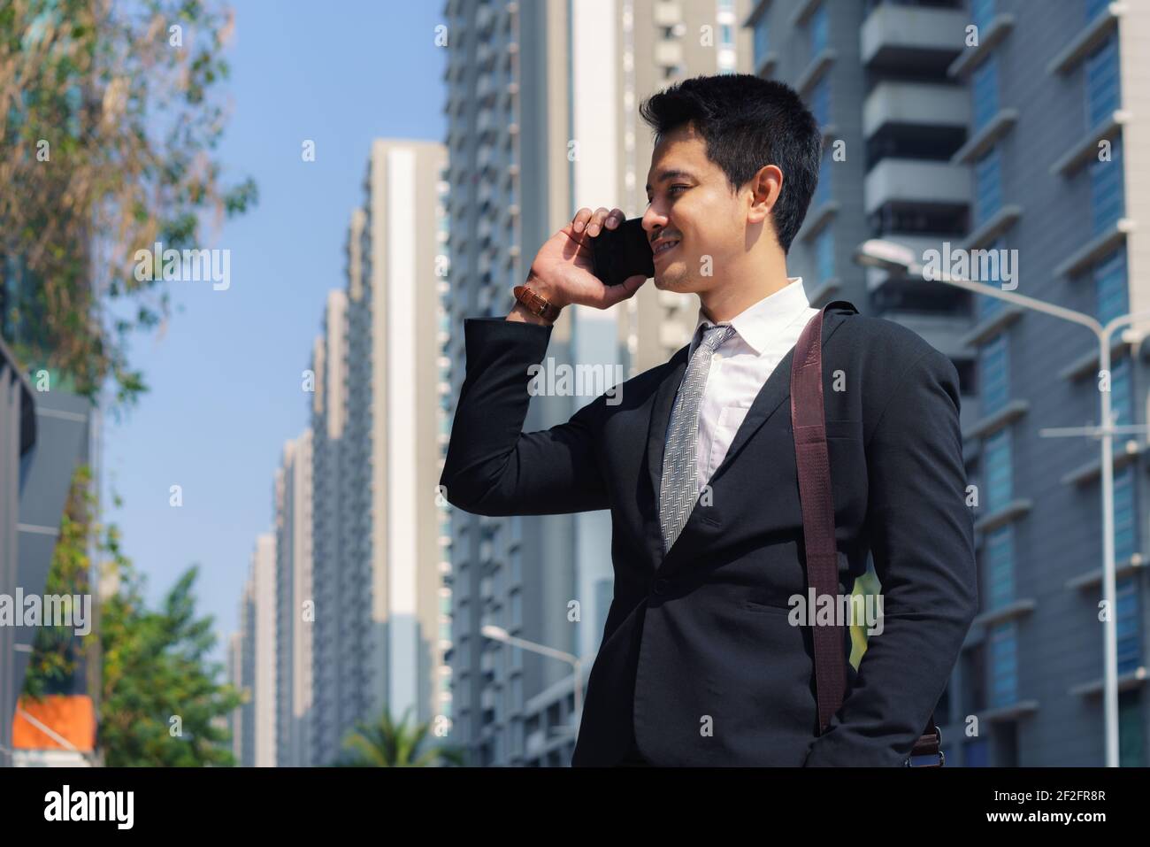 Asiatische Geschäftsmann steht und im Gespräch mit seinem Kollegen in Telefon auf den Straßen der Stadt während der morgendlichen pendeln. Stockfoto