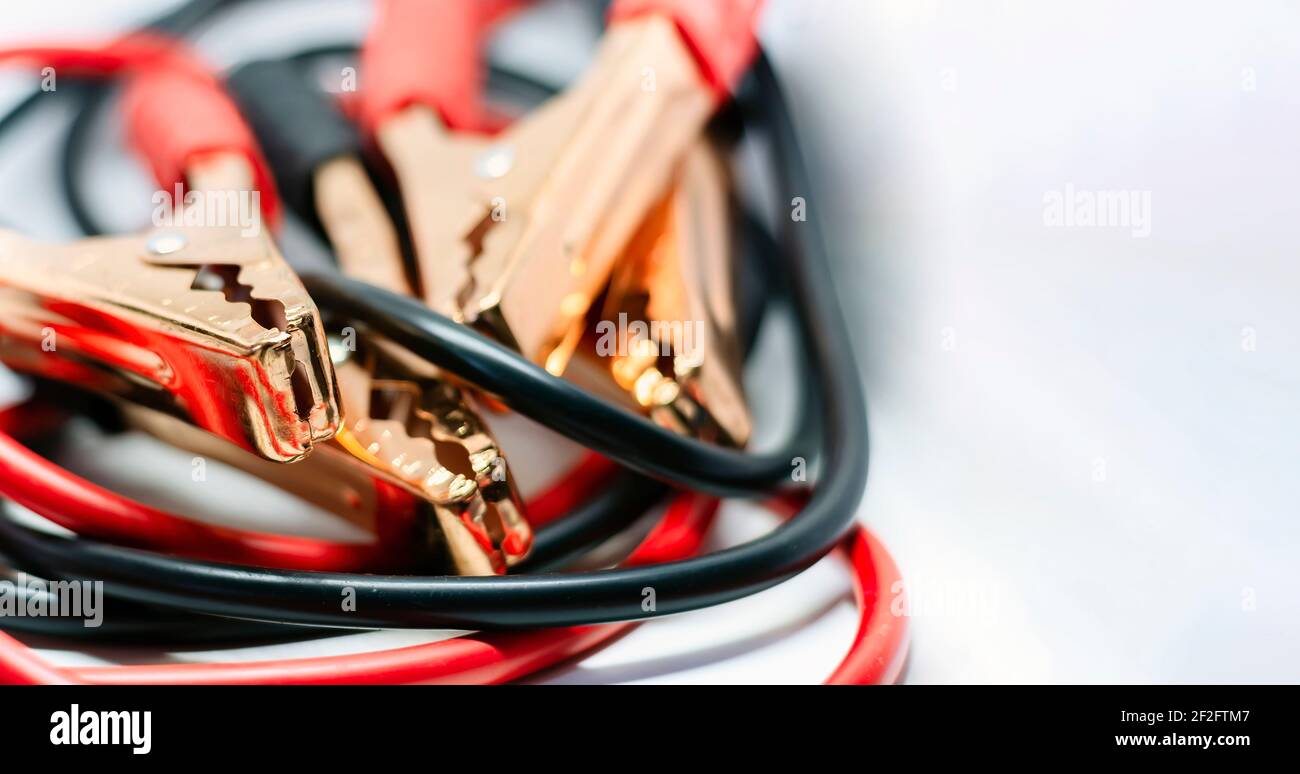 Nahaufnahme des roten und schwarzen Autobatterie-Jumper-Kabels, isoliert auf weißem Hintergrund. Ladekabel. Konzentrieren Sie sich auf Metall Stockfoto