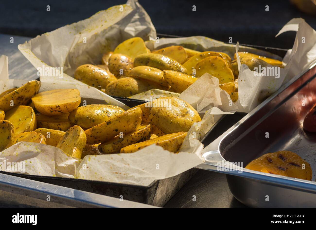Street Food in der Ukraine - gegrillte Kartoffeln liegen auf einem Metalltablett in Pergamentpapier und bereit zu sein Serviert Stockfoto