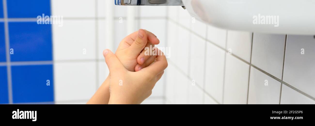 Kinderhände mit Lufttrockner in öffentlichen Toiletten oder Waschräumen. Banner Stockfoto