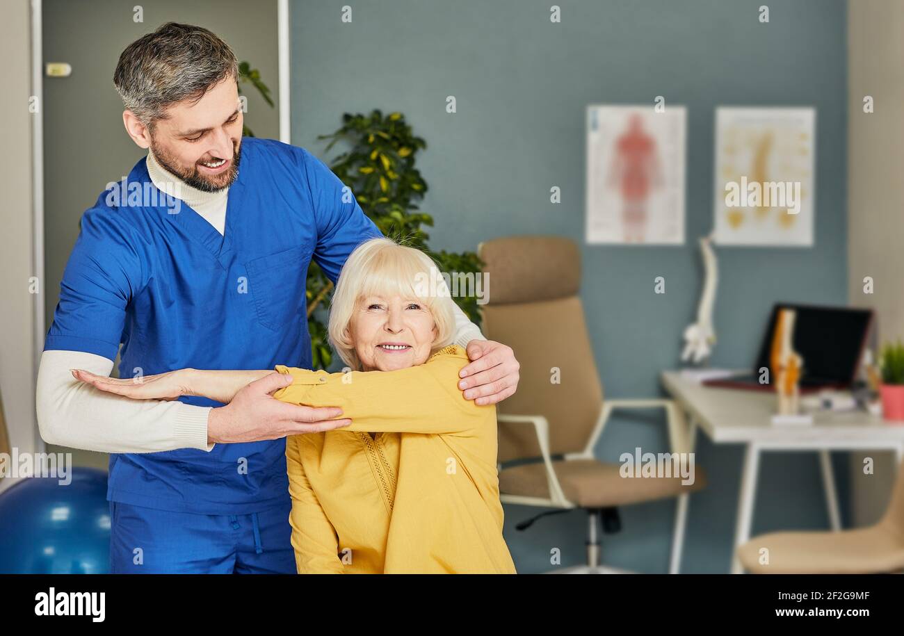 Physiotherapeut hilft bei der Behandlung eines Handgelenks für einen älteren Patienten. Physiotherapie, Behandlung in einem Sport-Gesundheitszentrum Stockfoto