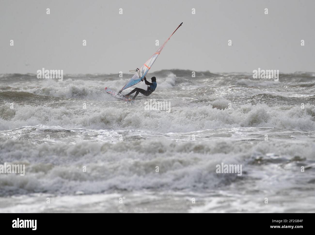 Ein Windsurfer surft im rauen Meer vor dem West Wittering Strand in West Sussex. Bilddatum: Freitag, 12. März 2021. Stockfoto