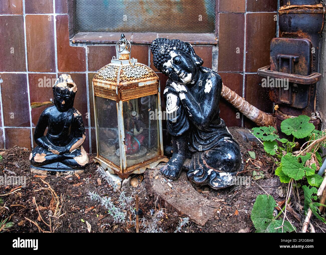 Ramponierter Buddha und rostige Lampe im vernachlässigten Stadtgarten in der Almstadtstraße, Mitte, Berlin Stockfoto