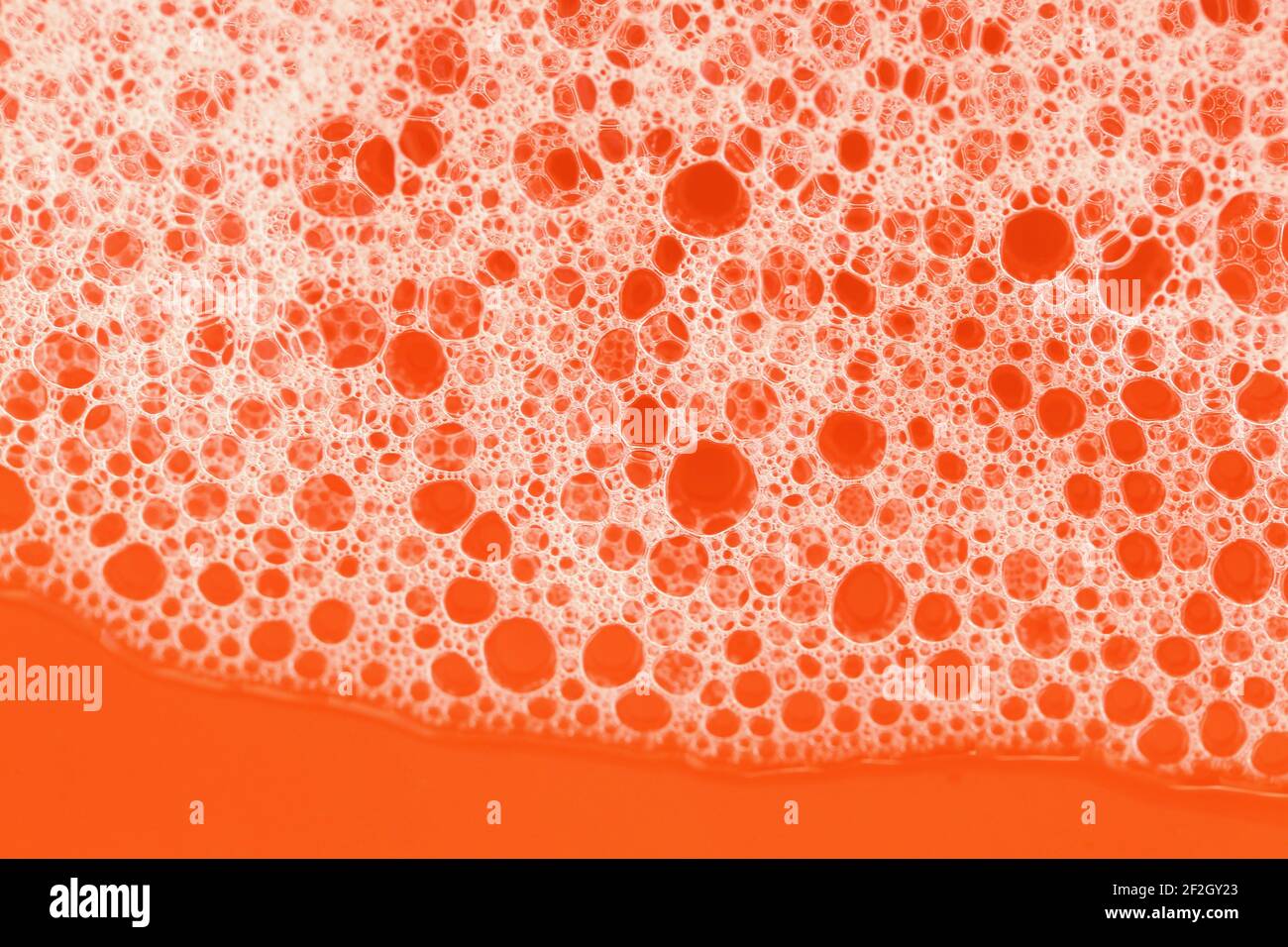 Seifenschaum Nahaufnahme auf orangefarbenem Hintergrund. Schönheit und Hygiene .Seifenschaum Makro .Seifenblasen.Badeschaum Stockfoto