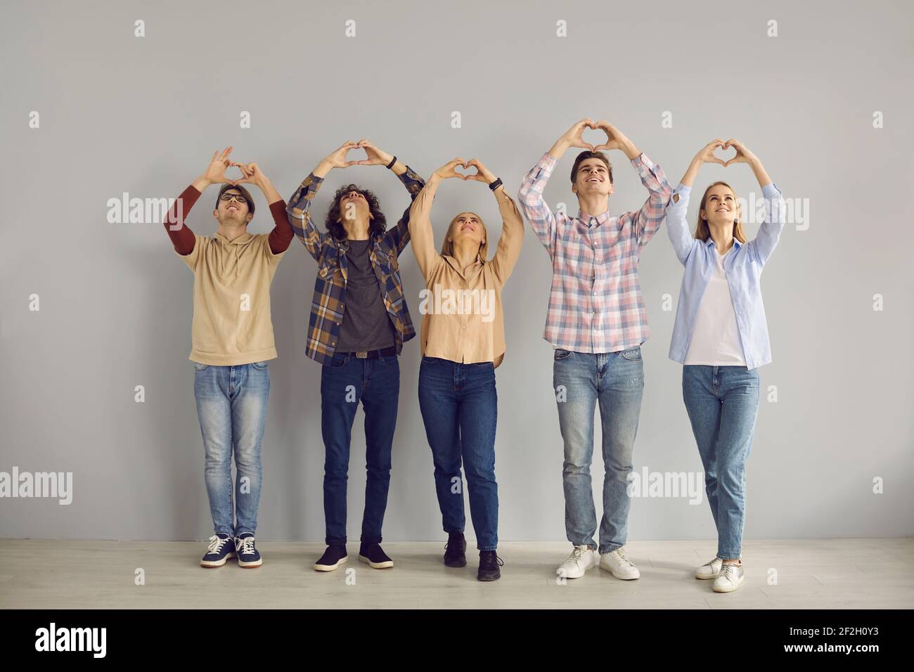 Eine Gruppe von Menschen drückt Dankbarkeit und Liebe aus, indem sie das Herz mit ihren Händen zusammenfalten und anheben. Stockfoto