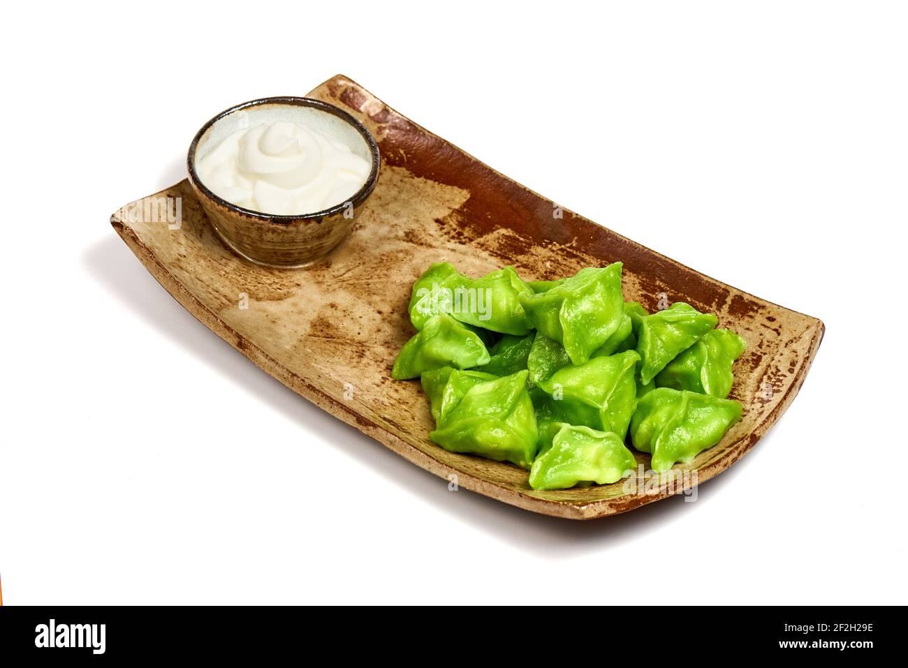 Grün Dim Sum auf einem Holzteller auf weißem Hintergrund. Stockfoto