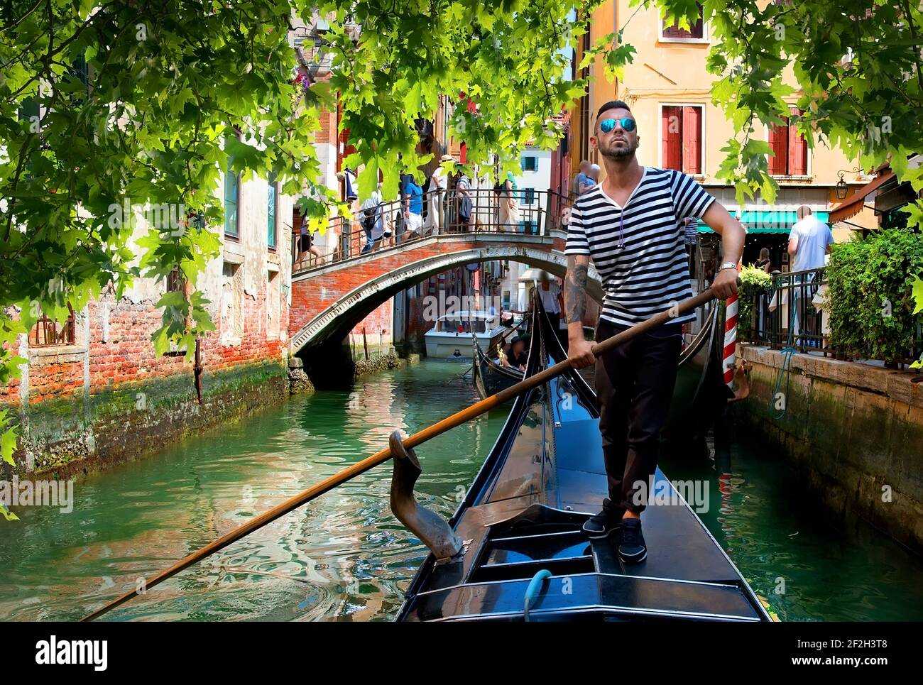 Gut aussehend Gondoliere während der Gondelfahrt auf der Straße von Venedig, Italien Stockfoto