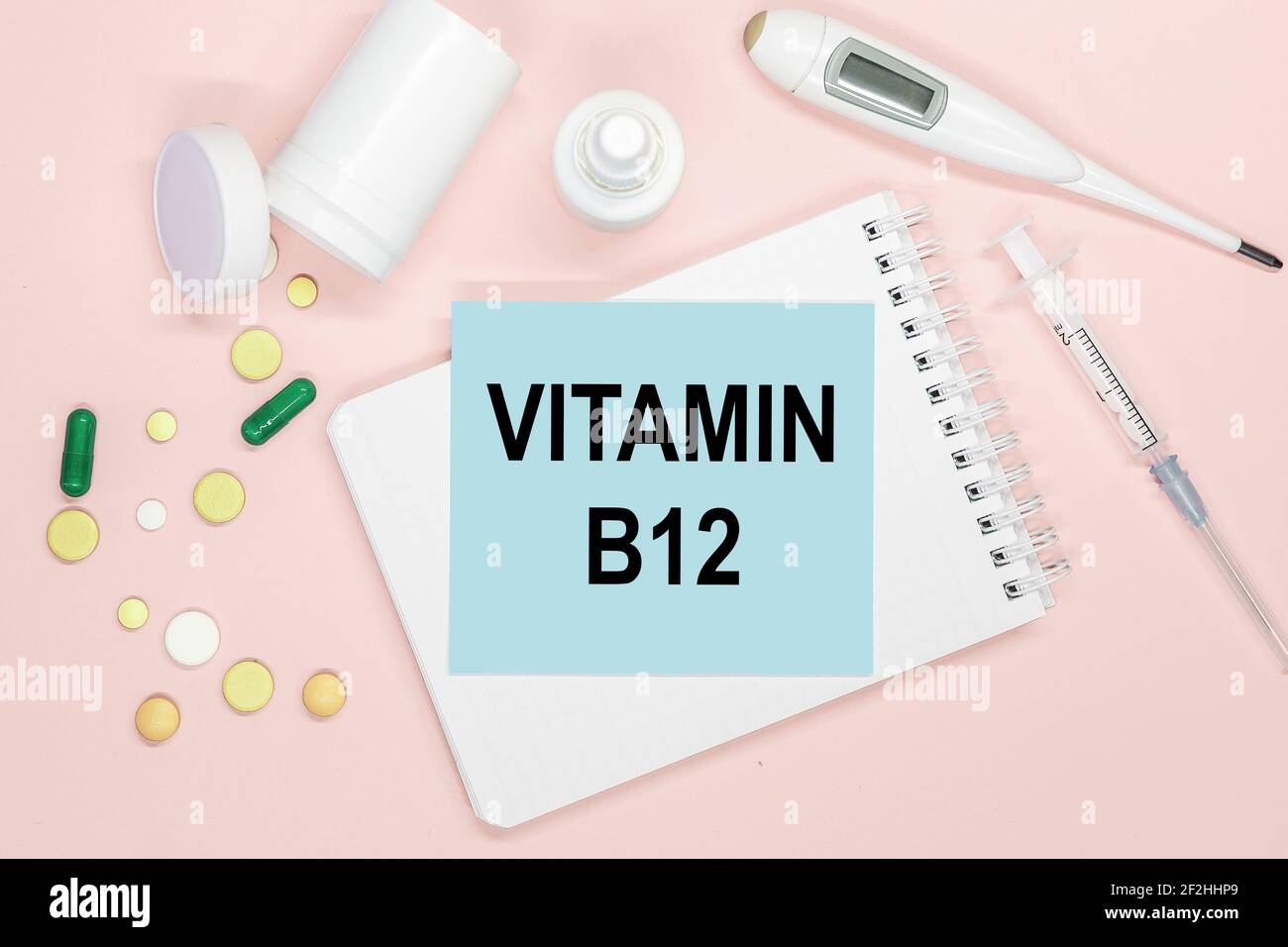 Notizbuchseite mit Text VITAMIN B12 auf einem Tisch mit Pillen und Spritze. Medizinisches Konzept. Stockfoto