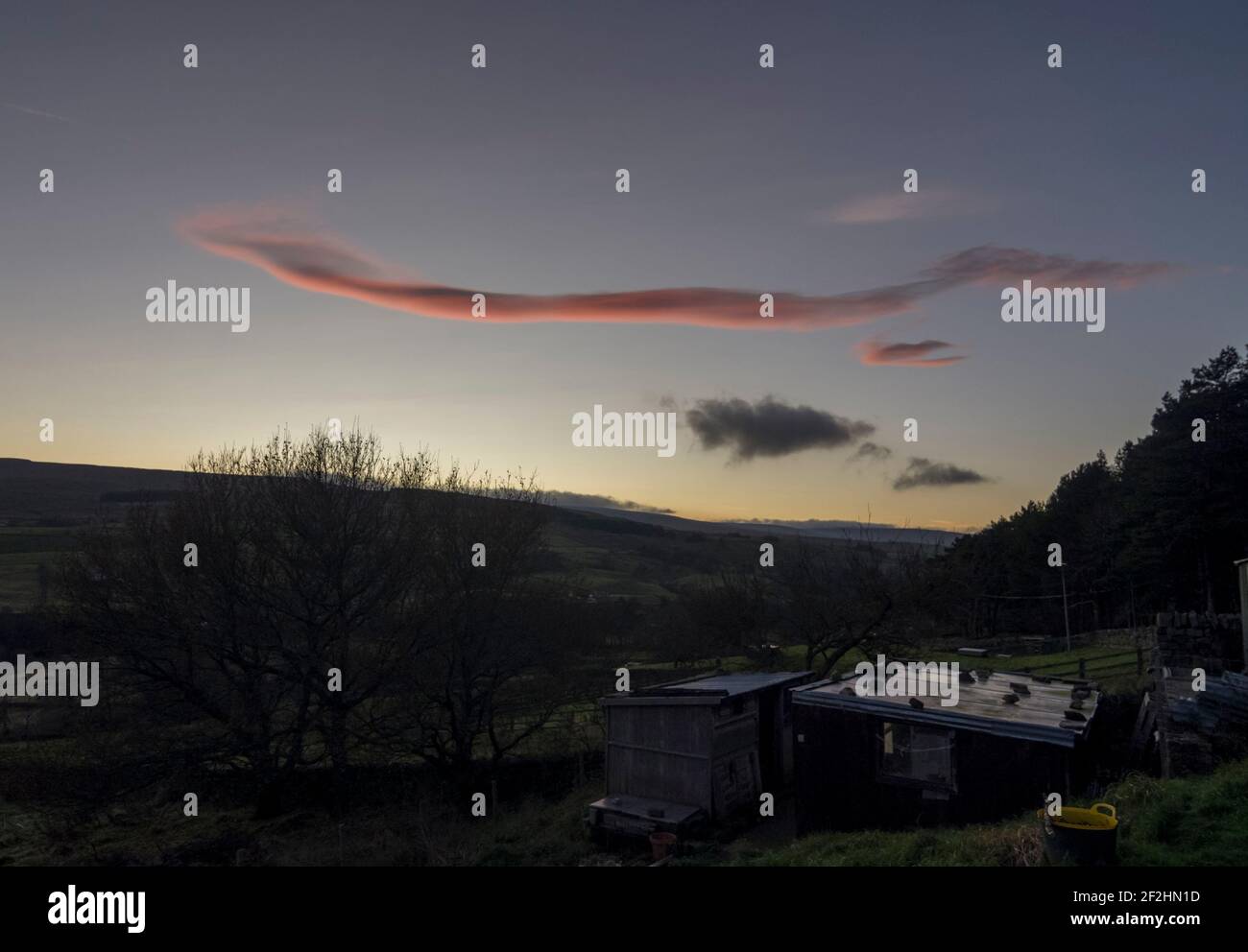 Eine längliche rosa Wolke (Cirrus ?) Über den North Pennine Hills (Weardale, County Durham, UK) bei Sonnenuntergang Stockfoto