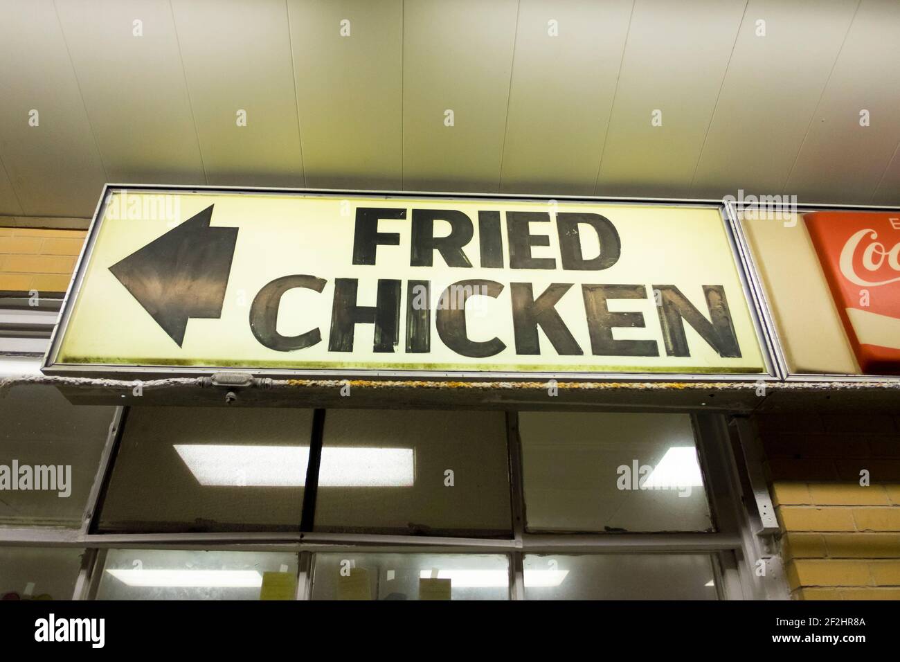 Ein Pfeil zeigt in Richtung Fried Chicken auf einem hinterleuchteten Schild in einem Fast-Food-Restaurant am Abend. Auf der Promenade in Rehoboth Beach, Delaware. Stockfoto