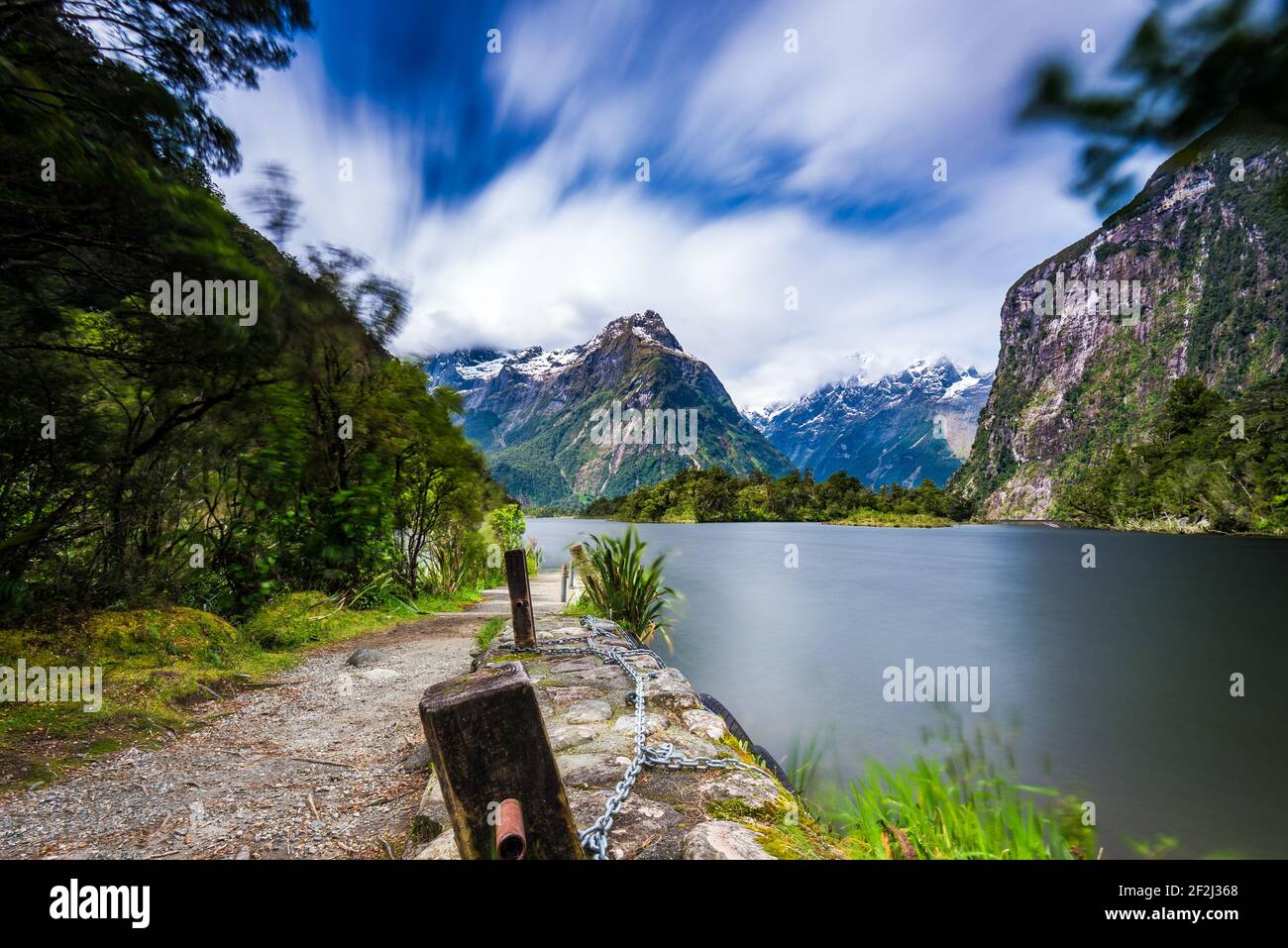 Der Milford Track-Pfad führt entlang der Wasseroberfläche. Steile Felswände über dem Wasser im Doubtful Sound Fjord, Neuseeland. Stockfoto