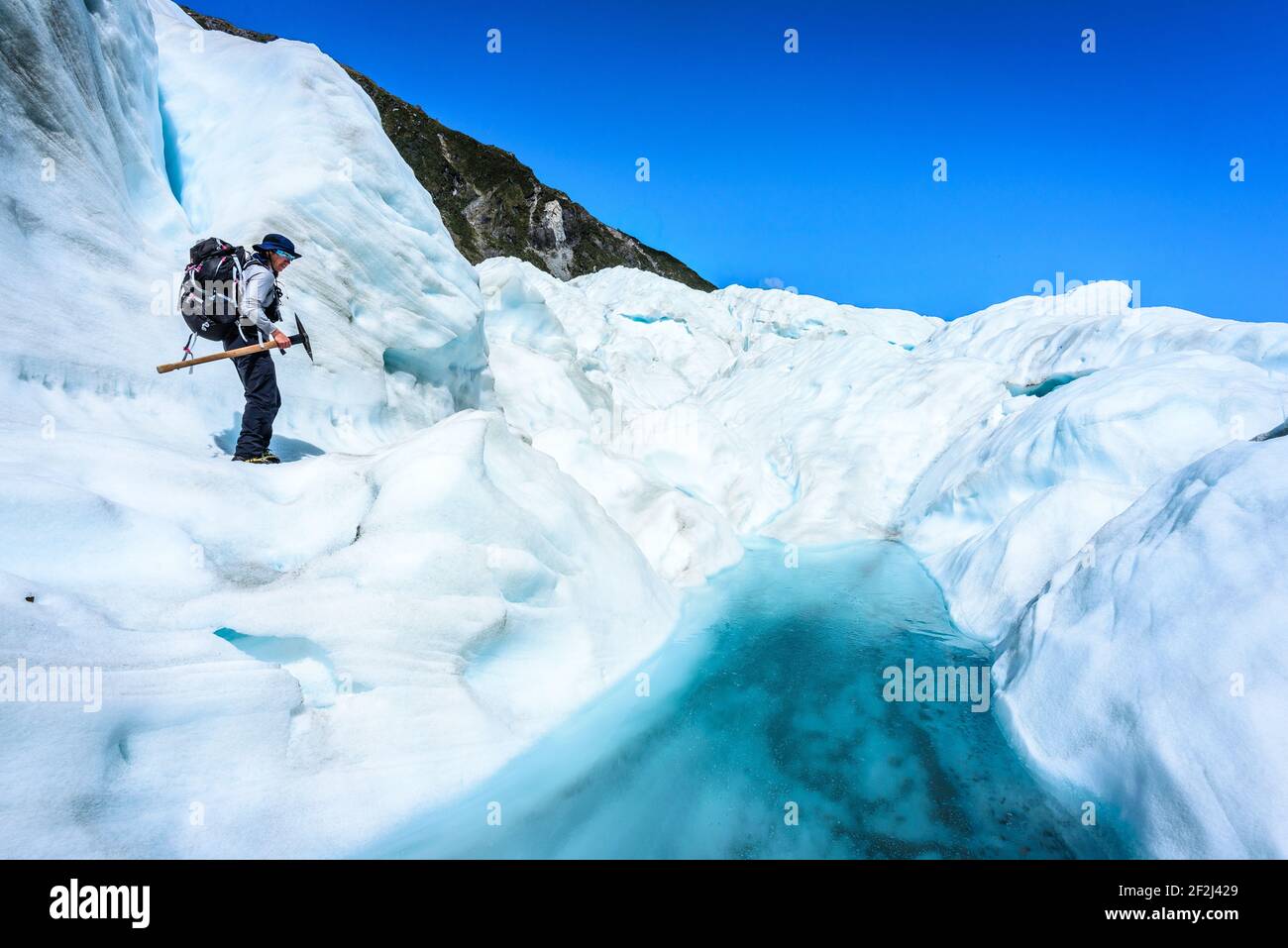 Eiskletterer, der sich auf Schnee und Eis auf dem Fox Glacier, South Island, Neuseeland, vorwärts bewegt. Sonniger Tag mit klarem Himmel. Stockfoto