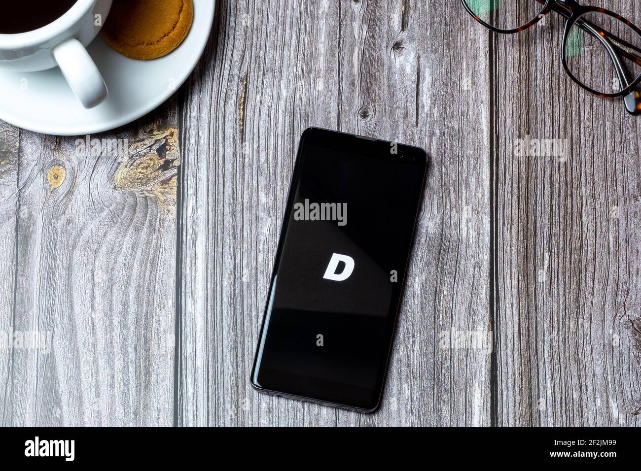 Ein Handy oder Handy auf einem Holz gelegt Tabelle mit der Tröpfchen Streetwear App auf dem Bildschirm geöffnet Stockfoto